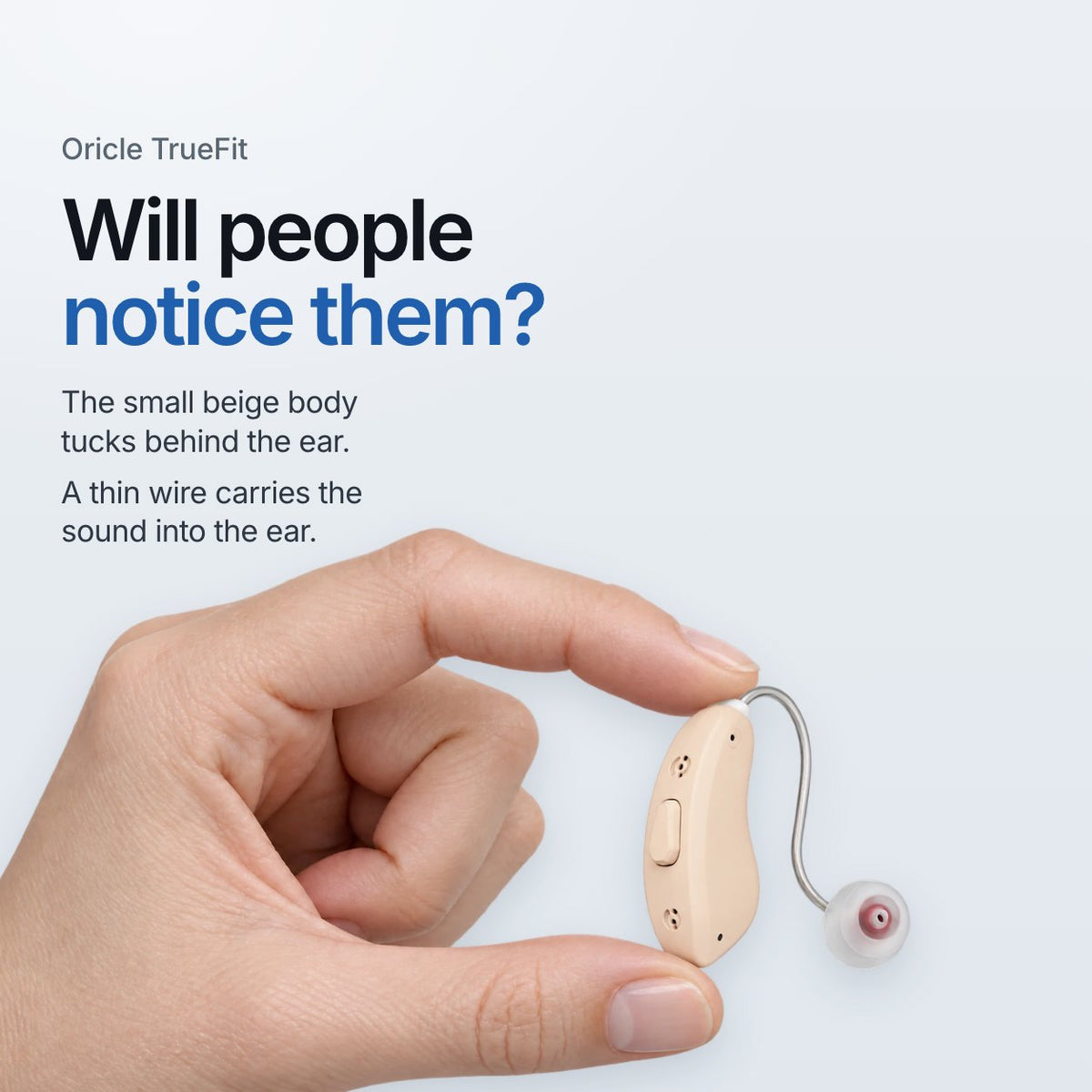 Oricle TrueFit. Will people notice them? The small beige body tucks behind the ear. A thin wire carries the sound into the ear. A hand holds one beige aid between finger and thumb