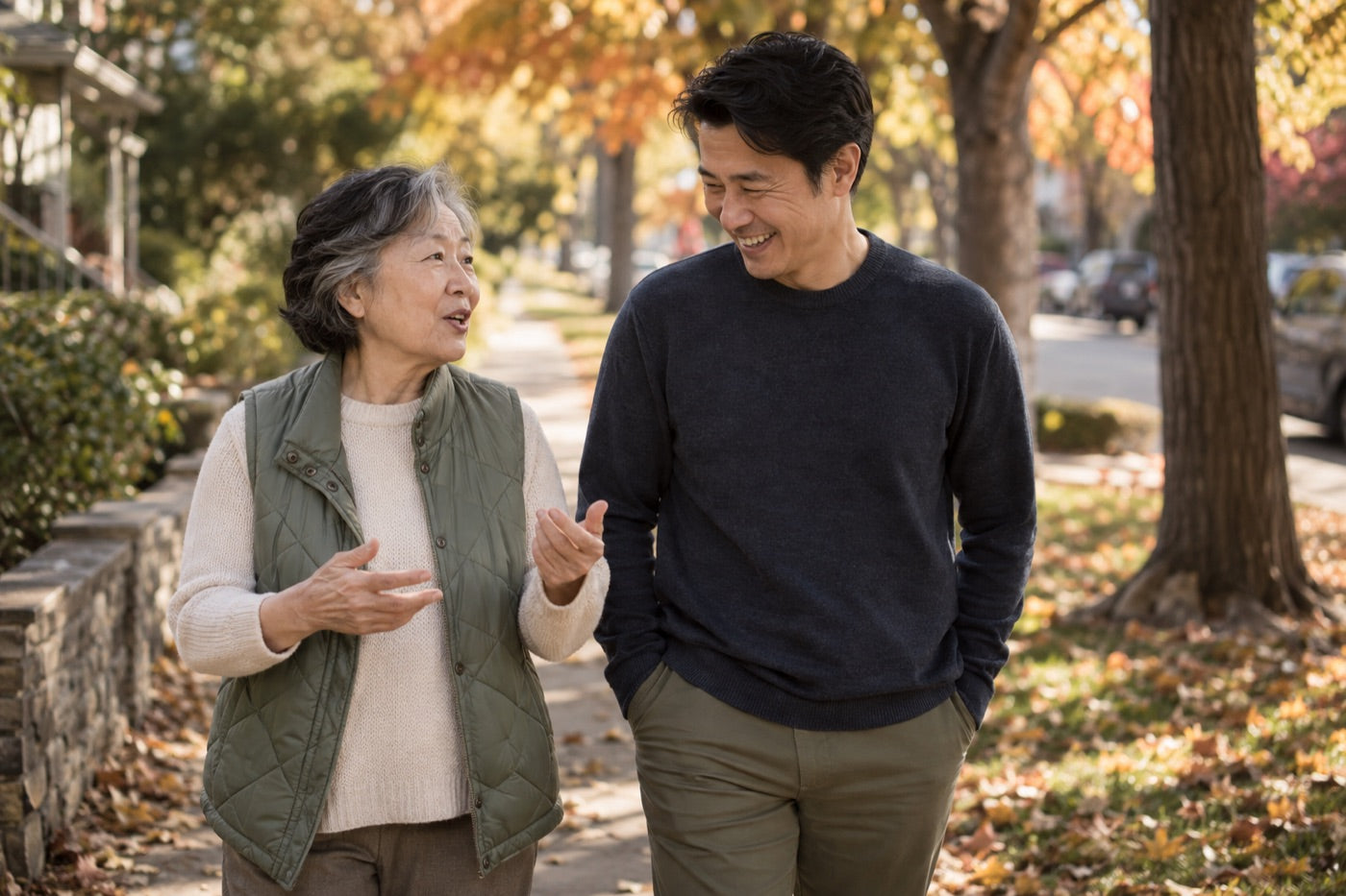 A mother and her adult son walking and talking on an autumn sidewalk